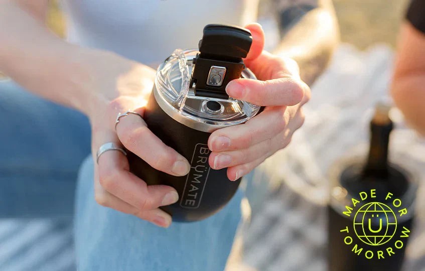BirdieBox Brumate Uncork'd XL black 14oz insulated wine tumbler with lid, held by hands outdoors.