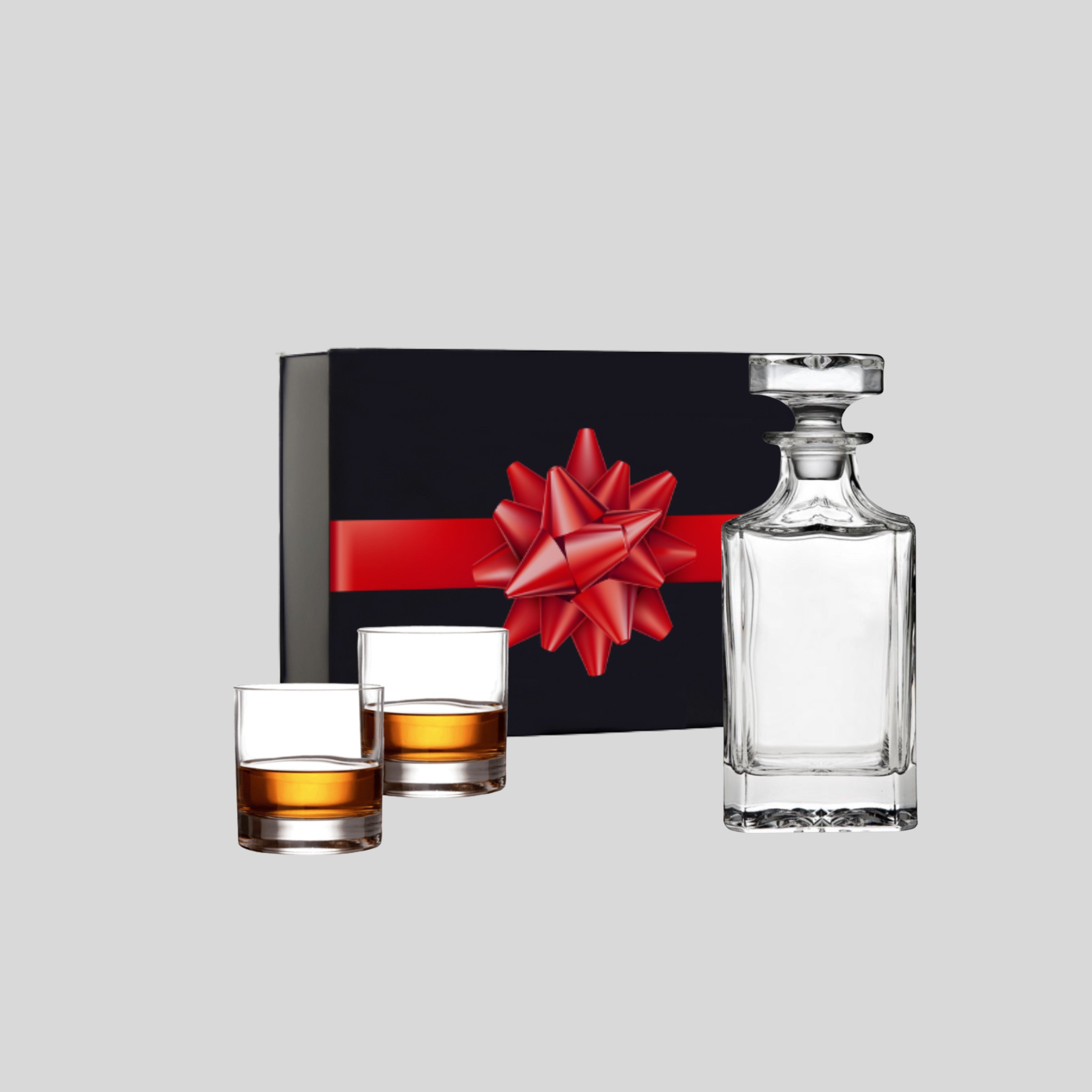 BirdieBox Holiday Cheers Gift Set: clear glass decanter and two rocks glasses filled with amber liquid, presented with a black gift box and red ribbon.