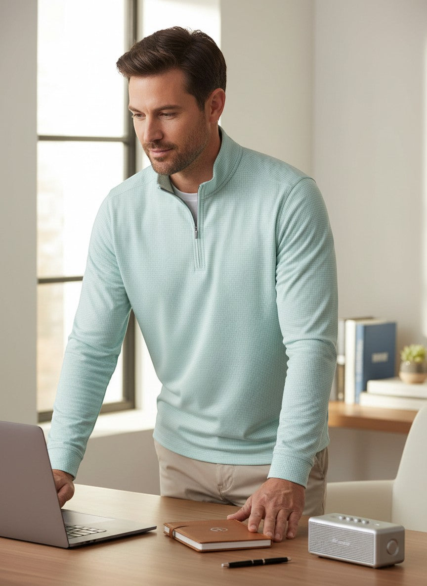 BirdieBox light blue performance quarter-zip pullover with subtle textured pattern, worn by a man at a desk.