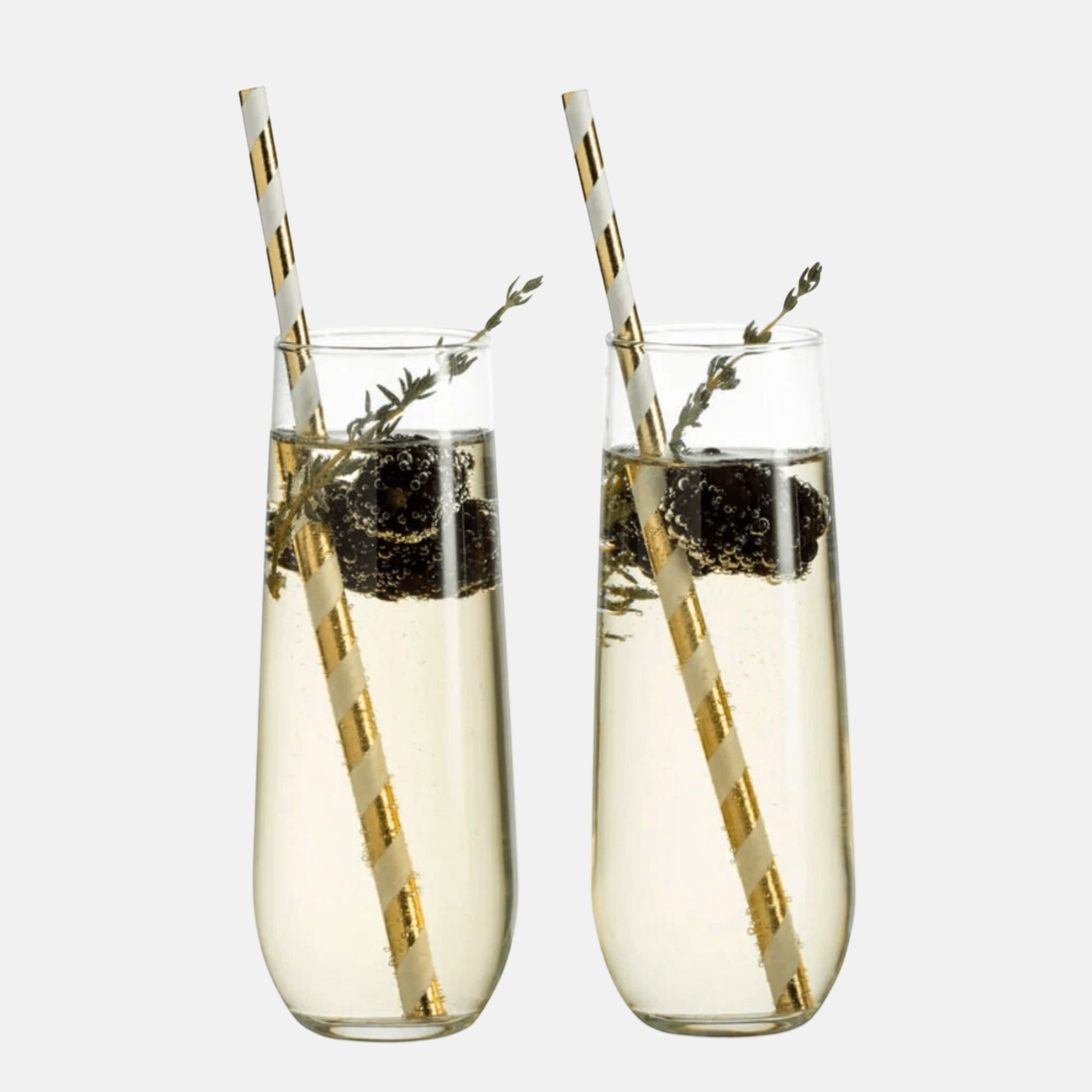 BirdieBox Old Tymes stemless flute glasses filled with champagne, blackberries, and thyme, featuring gold striped straws.