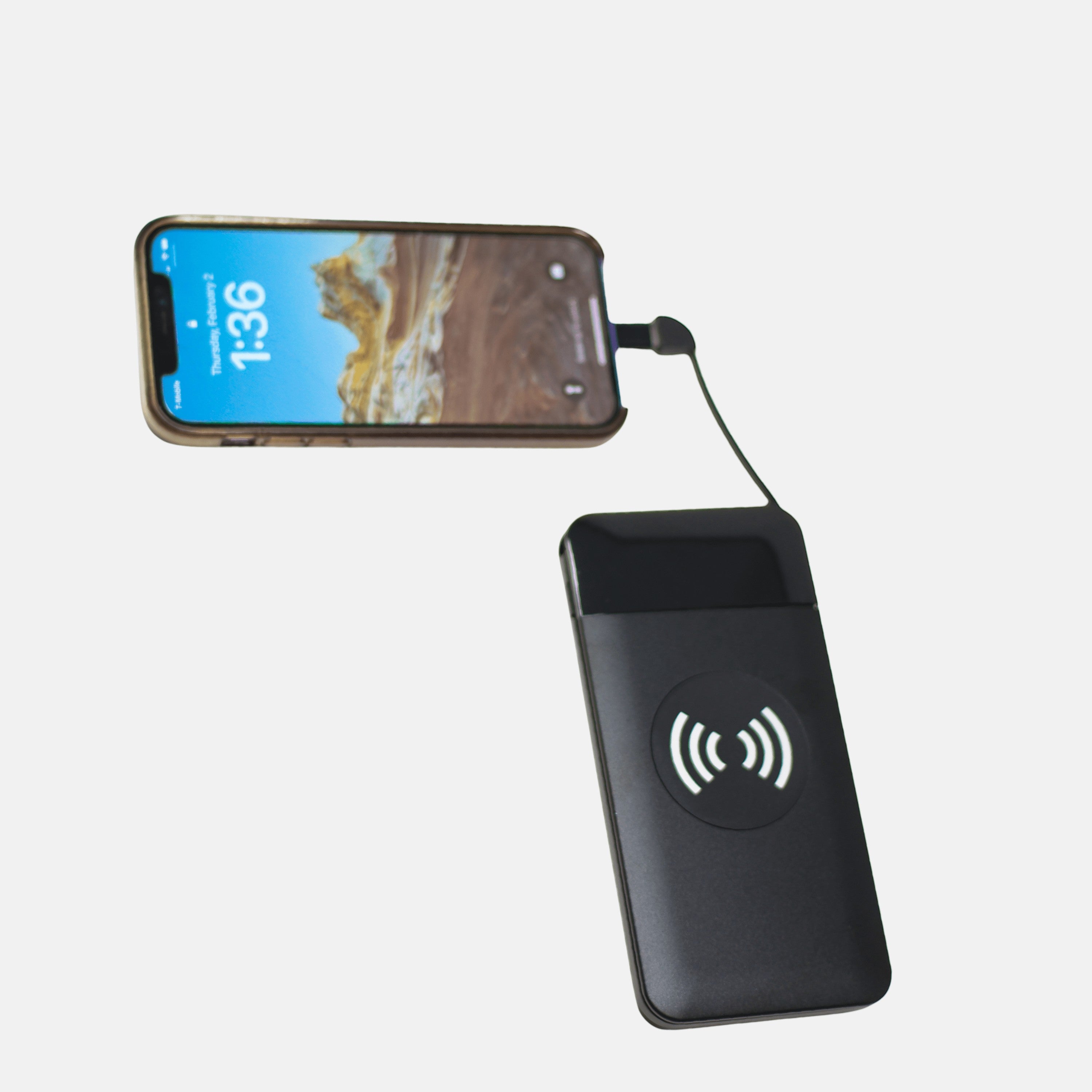 BirdieBox black 10,000 mAh Qi wireless power bank charging a smartphone. Features LED display and included USB cords.