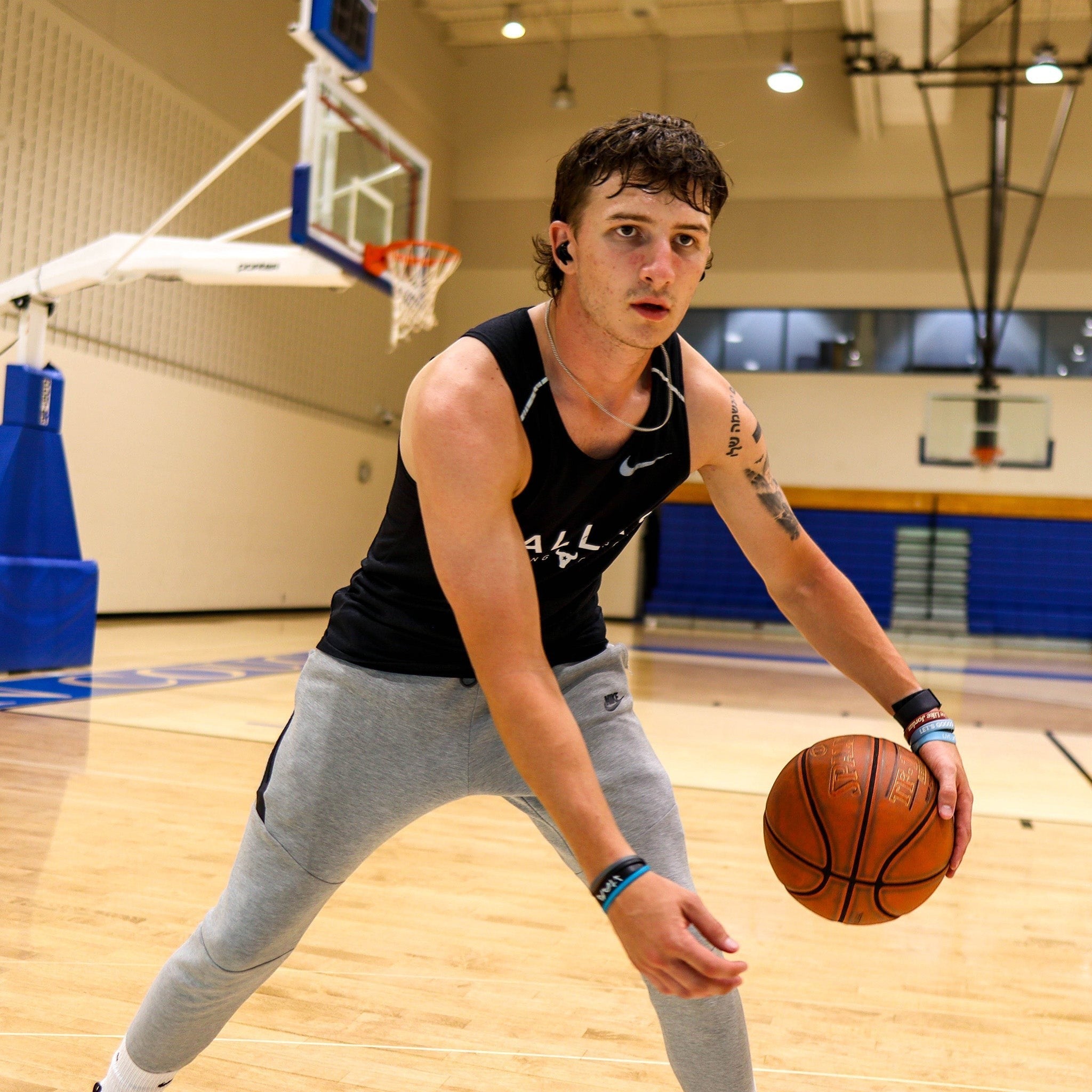 BirdieBox black wireless earbuds worn by a man playing basketball. Sweat-resistant and water-resistant for active use.