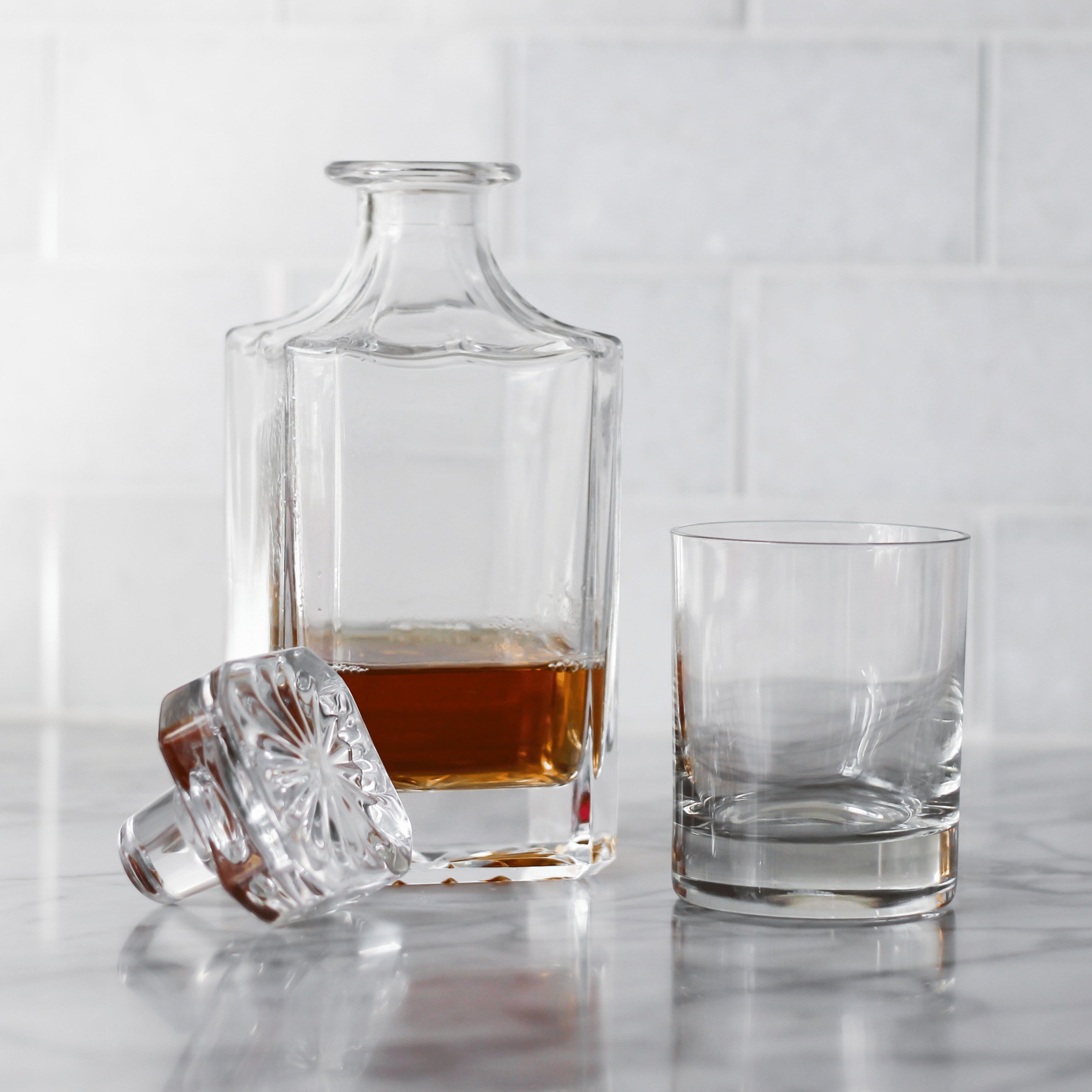 BirdieBox Old Tymes Crystal Decanter with a glass of whiskey on a marble countertop.